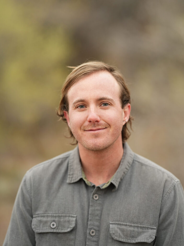 Portrait of queer affirming therapist Keegan Meadows standing outdoors in natural light.